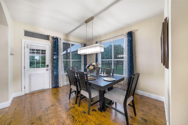 dining room featuring wood finished floors, baseboards, and arched walkways
