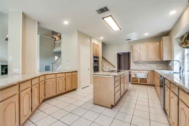 kitchen with light brown cabinetry, a sink, a kitchen island, decorative backsplash, and light stone countertops