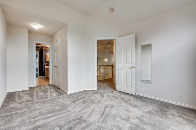 unfurnished bedroom with carpet, baseboards, lofted ceiling, and ensuite bath