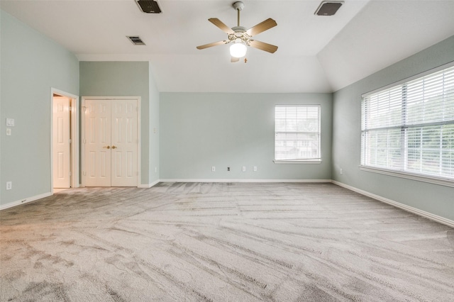 carpeted empty room with vaulted ceiling, ceiling fan, and baseboards