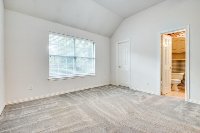unfurnished bedroom with vaulted ceiling, carpet, baseboards, and connected bathroom