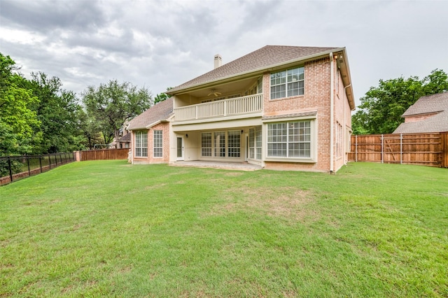 back of property with a balcony, a ceiling fan, a chimney, a patio area, and brick siding