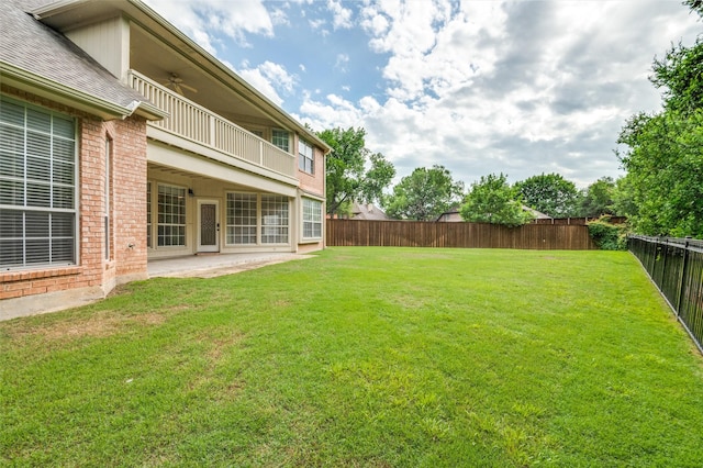 view of yard featuring a balcony, ceiling fan, and a patio