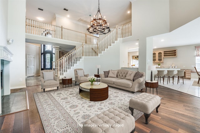 living area with stairway, a high ceiling, a chandelier, wood finished floors, and baseboards