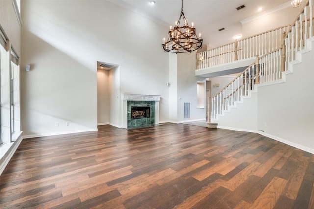 unfurnished living room featuring dark wood-type flooring, stairs, a towering ceiling, baseboards, and a fireplace