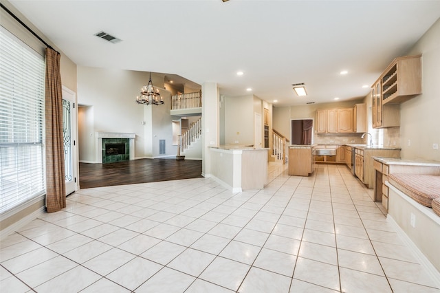 kitchen featuring light brown cabinetry, open floor plan, light tile patterned floors, recessed lighting, and a high end fireplace