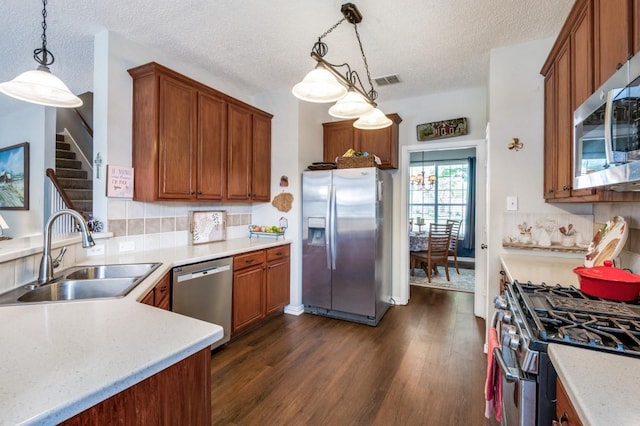 10557 Stargazer Dr, Frisco, TX 75033 - kitchen with appliances with stainless steel finishes, a sink, a textured ceiling, dark wood-type flooring, and light countertops
