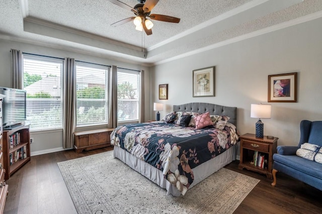 bedroom with a tray ceiling, ornamental molding, hardwood / wood-style floors, a textured ceiling, and baseboards