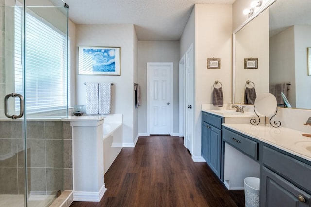 full bath with wood finished floors, a stall shower, double vanity, and a bath