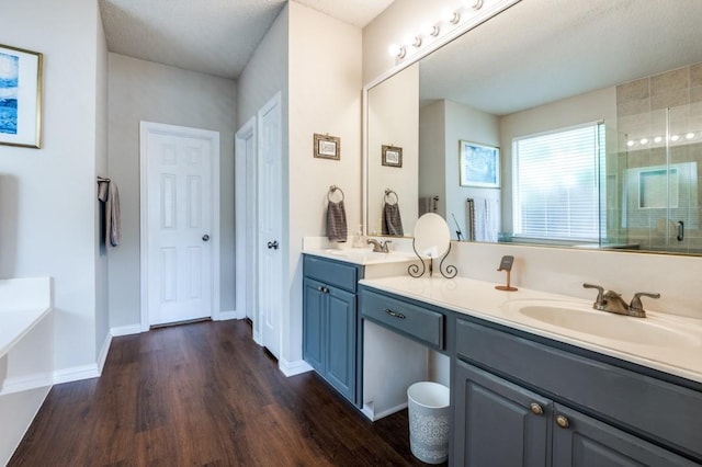 bathroom with wood finished floors, double vanity, a garden tub, and an enclosed shower