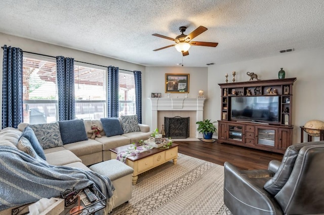 living area with a textured ceiling, wood finished floors, a ceiling fan, and a tiled fireplace