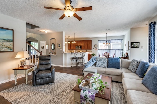 living area with a chandelier, arched walkways, a textured ceiling, dark wood-type flooring, and a ceiling fan