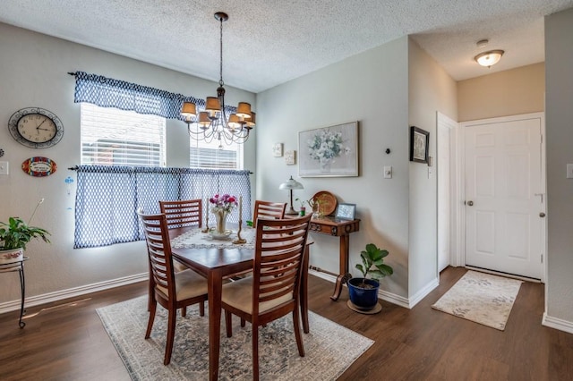 dining space featuring wood finished floors, a chandelier, baseboards, and a textured ceiling