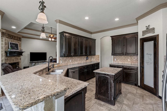 kitchen featuring a sink, a stone fireplace, stainless steel dishwasher, a ceiling fan, and crown molding