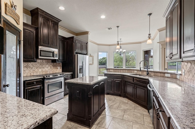 kitchen with appliances with stainless steel finishes, a sink, tasteful backsplash, a chandelier, and a peninsula