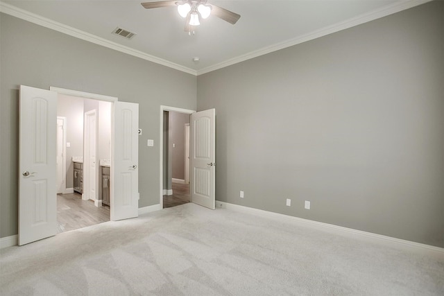 unfurnished bedroom featuring light colored carpet, baseboards, crown molding, ensuite bathroom, and a ceiling fan