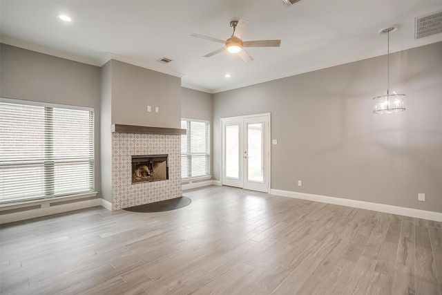 unfurnished living room featuring a ceiling fan, a tile fireplace, baseboards, ornamental molding, and light wood-type flooring