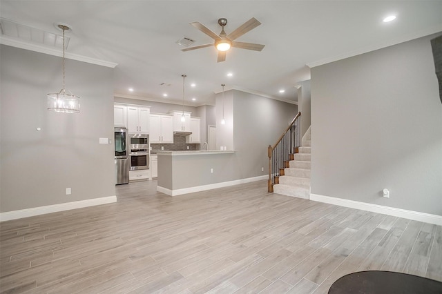 unfurnished living room with crown molding, a ceiling fan, baseboards, light wood finished floors, and stairs