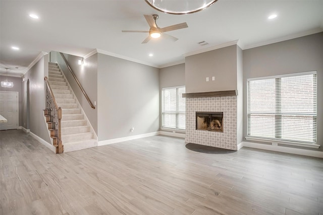 unfurnished living room with baseboards, a ceiling fan, crown molding, stairway, and light wood-style floors