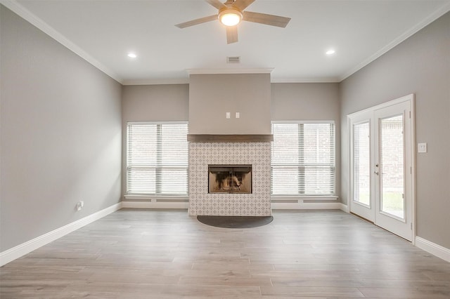 unfurnished living room with a tile fireplace, ceiling fan, baseboards, light wood finished floors, and crown molding