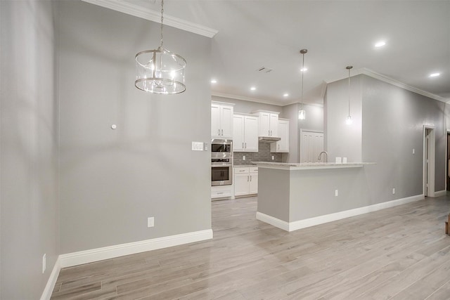 kitchen with crown molding, backsplash, stainless steel microwave, light wood finished floors, and white cabinets