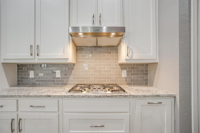 kitchen featuring stainless steel gas cooktop, ventilation hood, white cabinetry, and tasteful backsplash