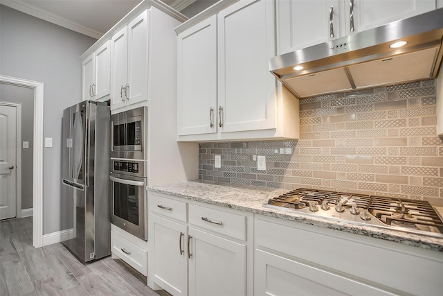 kitchen with appliances with stainless steel finishes, ventilation hood, ornamental molding, white cabinetry, and backsplash