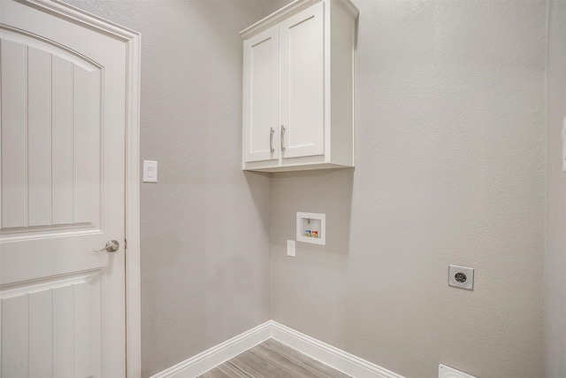 laundry area featuring electric dryer hookup, baseboards, hookup for a washing machine, cabinet space, and light wood-style flooring