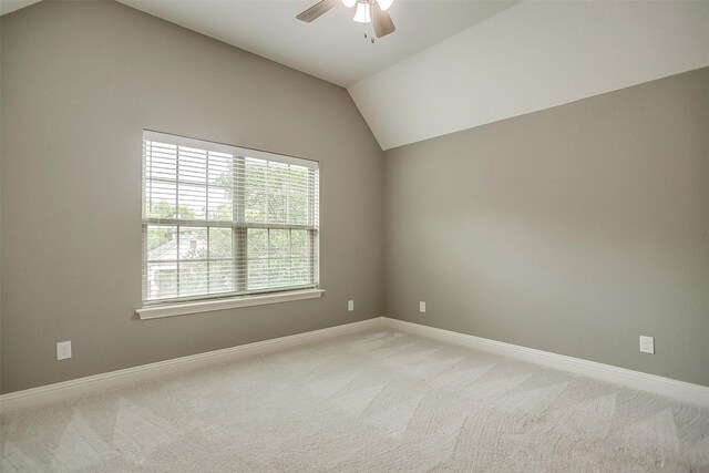 empty room with a ceiling fan, lofted ceiling, light carpet, and baseboards