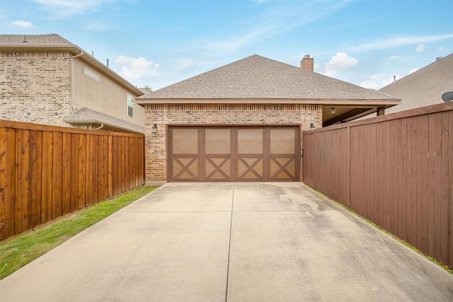 garage with concrete driveway and fence