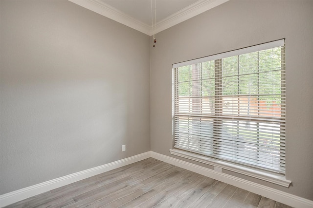 spare room with healthy amount of natural light, ornamental molding, baseboards, and light wood-type flooring
