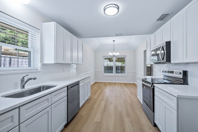 609 W Windsor Dr, Denton, TX 76207 - kitchen featuring appliances with stainless steel finishes, a sink, a chandelier, healthy amount of natural light, and vaulted ceiling