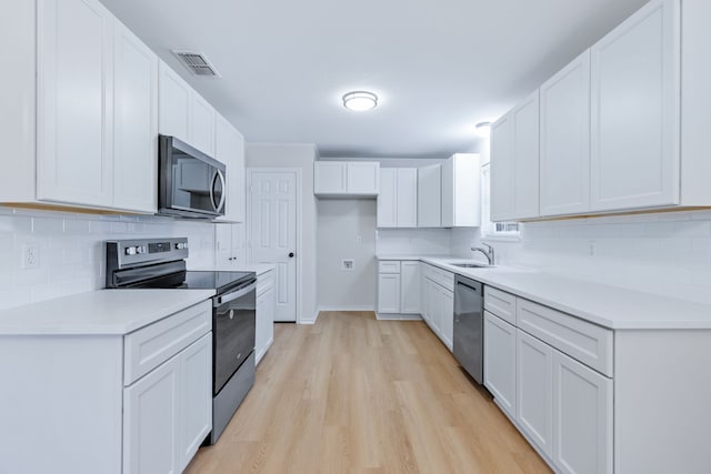 609 W Windsor Dr, Denton, TX 76207 - kitchen featuring appliances with stainless steel finishes, a sink, light wood finished floors, tasteful backsplash, and light countertops