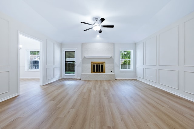609 W Windsor Dr, Denton, TX 76207 - unfurnished living room featuring a decorative wall, ceiling fan, light wood-style flooring, and a fireplace