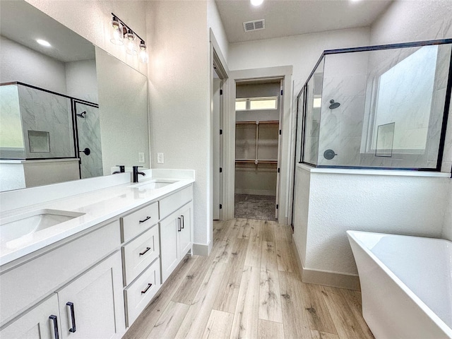 196 Jim Walter Dr, Runaway Bay, TX 76426 - bathroom featuring a stall shower, wood finished floors, a soaking tub, a walk in closet, and double vanity