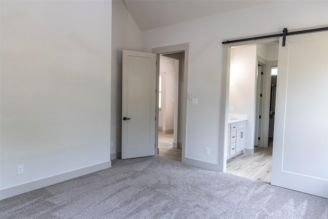 196 Jim Walter Dr, Runaway Bay, TX 76426 - unfurnished bedroom featuring light colored carpet, baseboards, and a barn door