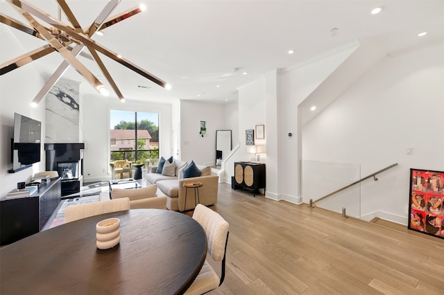 dining room featuring light wood-style floors, recessed lighting, a large fireplace, and baseboards