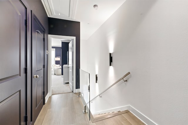 hall featuring attic access, light wood finished floors, and baseboards