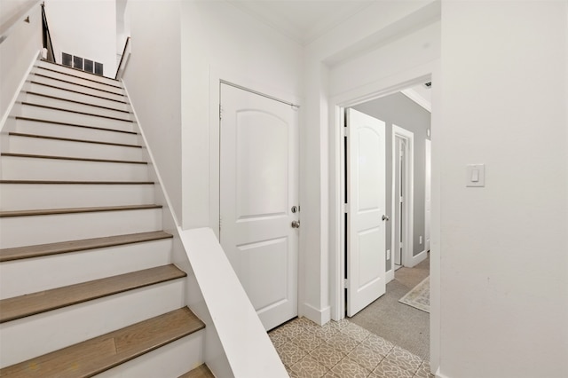 stairway featuring tile patterned floors, crown molding, and baseboards
