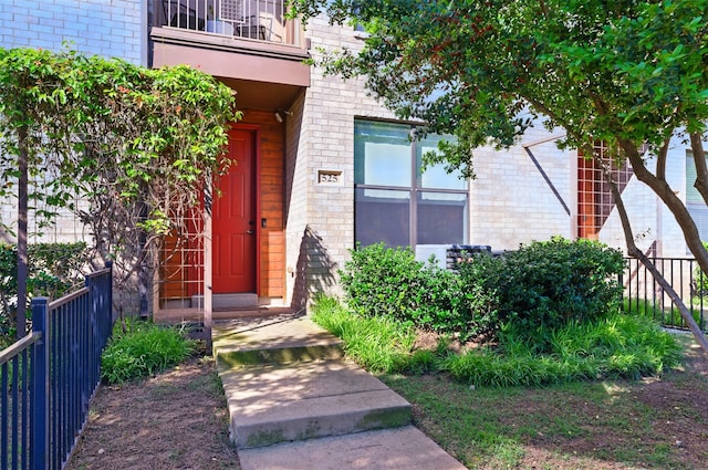 doorway to property featuring brick siding and fence