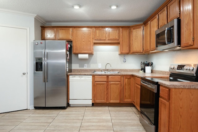 kitchen with appliances with stainless steel finishes, a sink, crown molding, a textured ceiling, and brown cabinetry