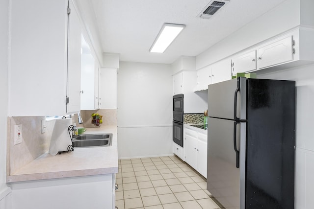 1710 Windsor Dr, Arlington, TX 76012 - kitchen featuring freestanding refrigerator, a sink, white cabinetry, backsplash, and light countertops