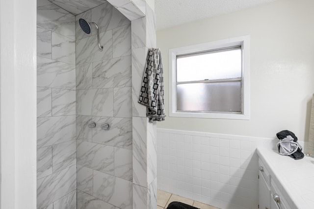 1710 Windsor Dr, Arlington, TX 76012 - bathroom featuring a tile shower, tile walls, a wainscoted wall, and a textured ceiling