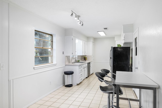 1710 Windsor Dr, Arlington, TX 76012 - kitchen with stainless steel dishwasher, a sink, freestanding refrigerator, light countertops, and white cabinets