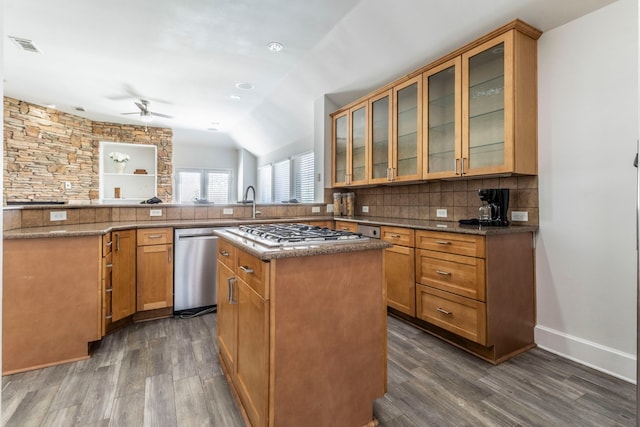 kitchen featuring dark wood-type flooring, ceiling fan, gas cooktop, tasteful backsplash, and a peninsula