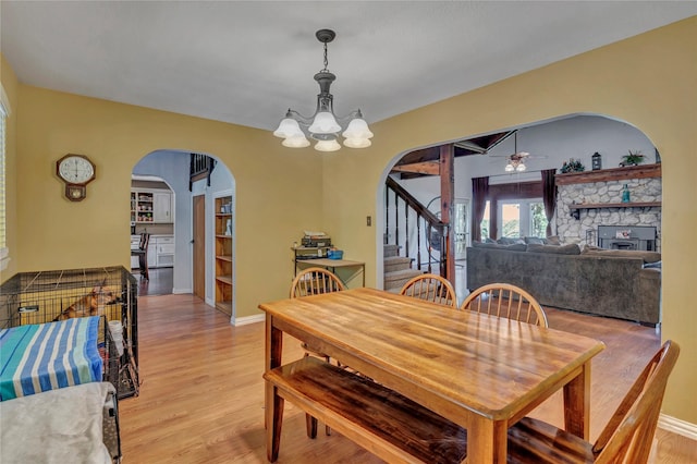 116 Nottingham Cir, Bridgeport, TX 76426 - dining space featuring arched walkways, a chandelier, stairway, and light wood-style floors