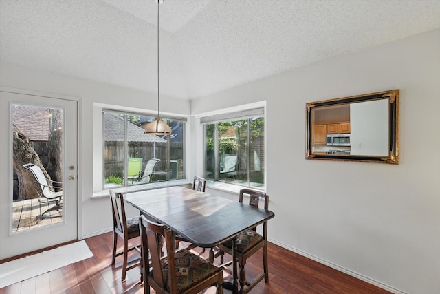 dining room with a textured ceiling, dark wood finished floors, and baseboards