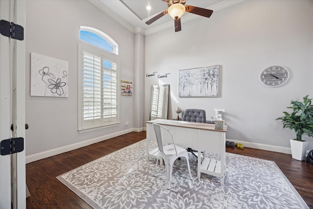 office area with ornamental molding, a ceiling fan, a high ceiling, wood finished floors, and baseboards