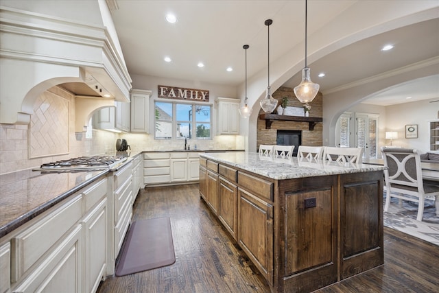 580 Butchart Dr, Prosper, TX 75078 - kitchen featuring stainless steel gas stovetop, open floor plan, dark wood-style floors, light stone counters, and a kitchen island