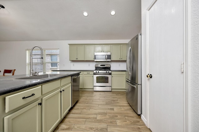 6717 Red Rock Trl, Watauga, TX 76137 - kitchen with appliances with stainless steel finishes, a sink, dark countertops, and light wood-style flooring